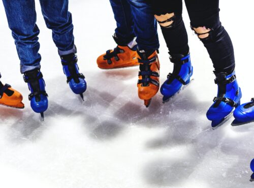 Feet Closeup Of Group Of Friends Ice Skating Together